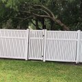 White vinyl semi-privacy fence with a gate and a fallen tree limb resting across the panels