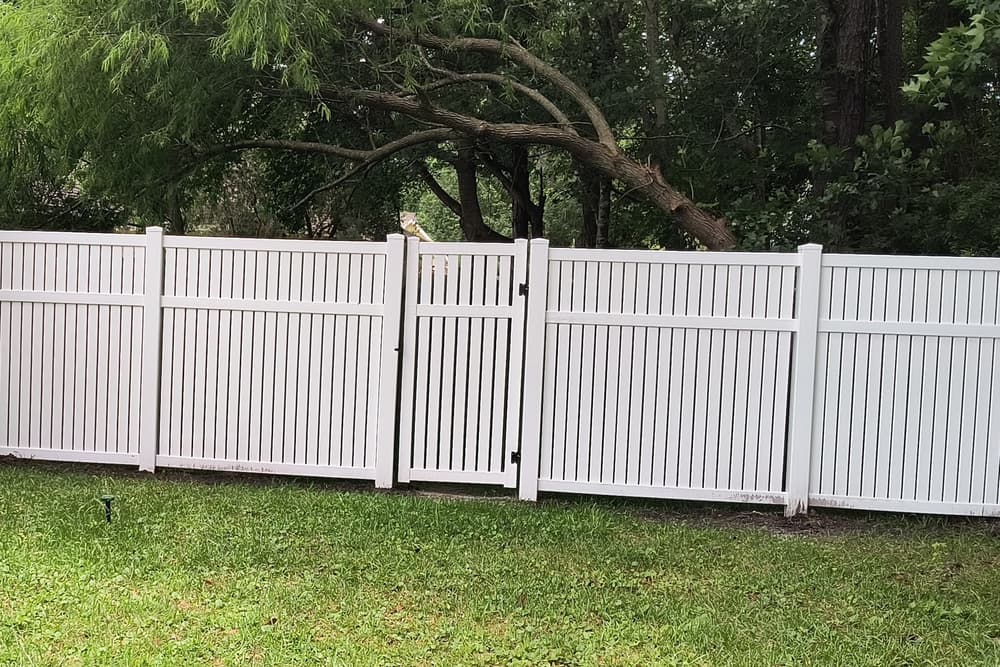 White vinyl semi-privacy fence with spaced top pickets and a matching gate across a lawn