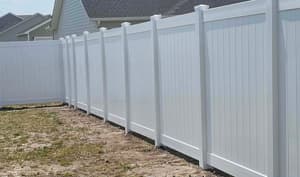 Long run of white vinyl privacy fence along the back of a lot in a newer subdivision
